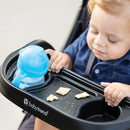 Load image into gallery viewer, Child using the tray on the Baby Trend XCEL-R8 PLUS Jogger Stroller with LED