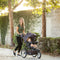 A mom is pushing her child in the Baby Trend XCEL-R8 PLUS Jogger Stroller with LED