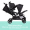 Baby Trend Sit N' Stand Double 2.0 Stroller travel system with an infant car seat attached to the rear seat
