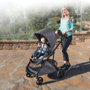 Load image into gallery viewer, A mom strolling her child in the Baby Trend Passport Switch Modular Stroller