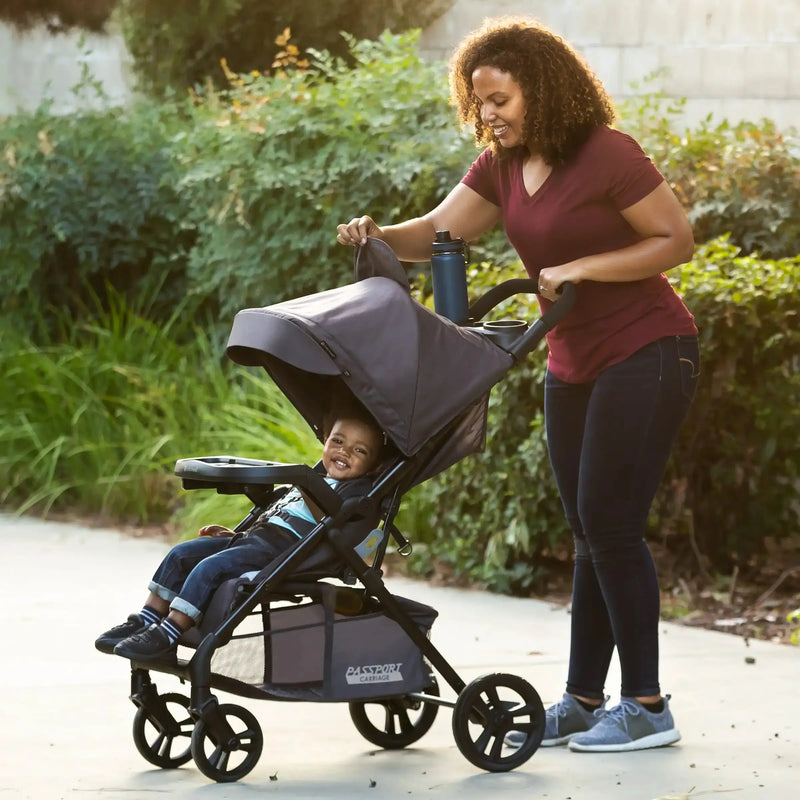 Mom is looking through the canopy peek-a-boo window to check on her child seating in the Baby Trend Passport Carriage Stroller