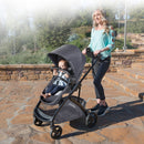 Load image into gallery viewer, A mom is pushing her baby in the Baby Trend Sonar Switch 6-in-1 Modular Stroller